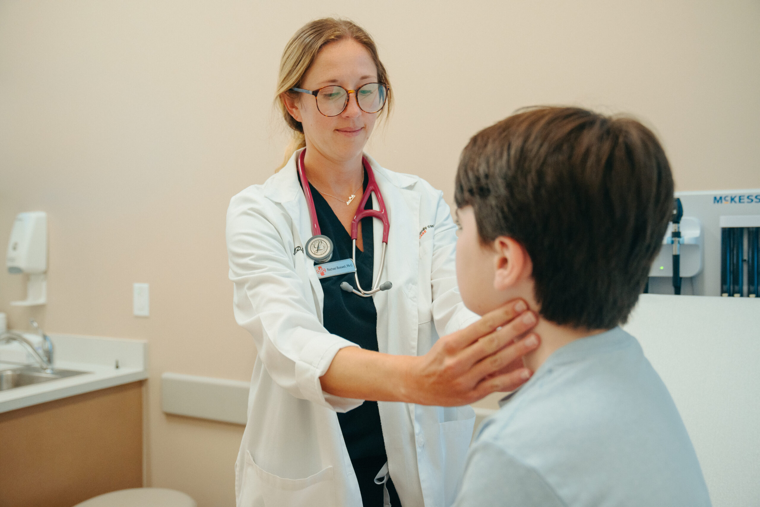 Female AFC provider checks child's lymph nodes, examining for RSV